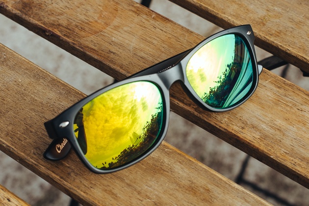 A pair of sunglasses rests on top of a wooden bench.